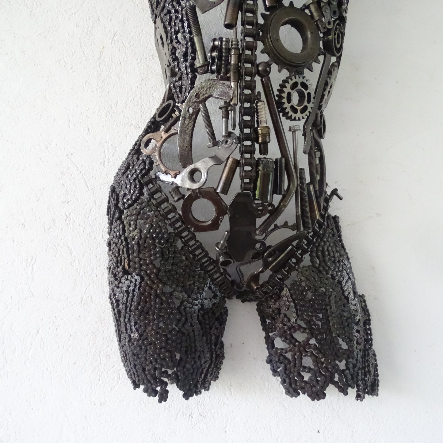 Détail base et jambes sculpture femme métal recyclé avec soudures apparentes et structure artisanale