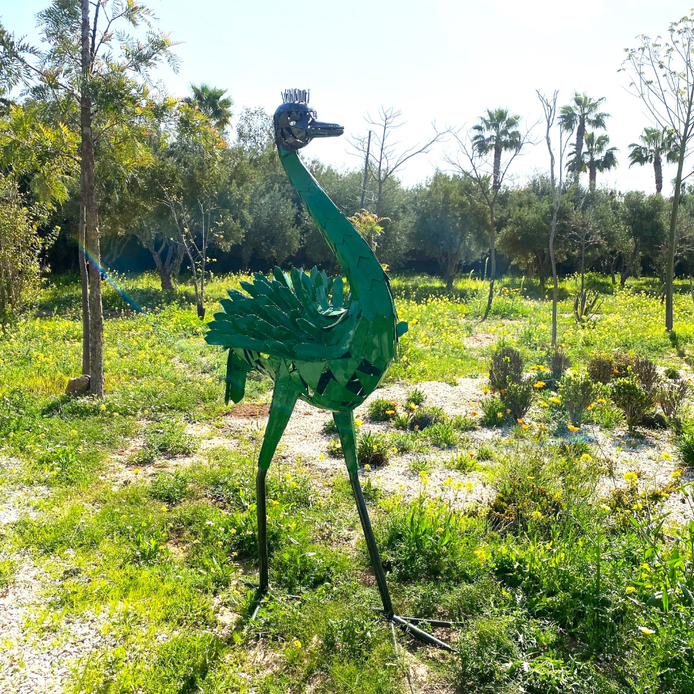 Vue côté droite sculpture autruche en métal recyclé dans un jardin avec structure métallique apparente