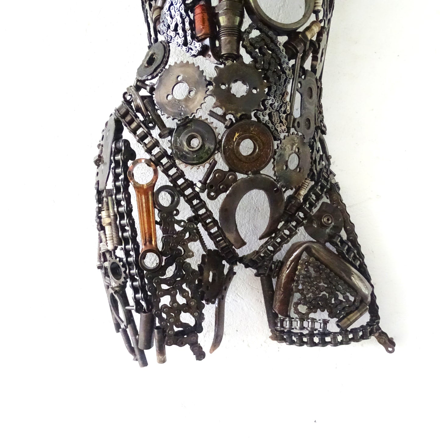 Détail de la partie inférieure d'un buste féminin en métal recyclé, assemblage artisanal avec jointures et nuances de surface