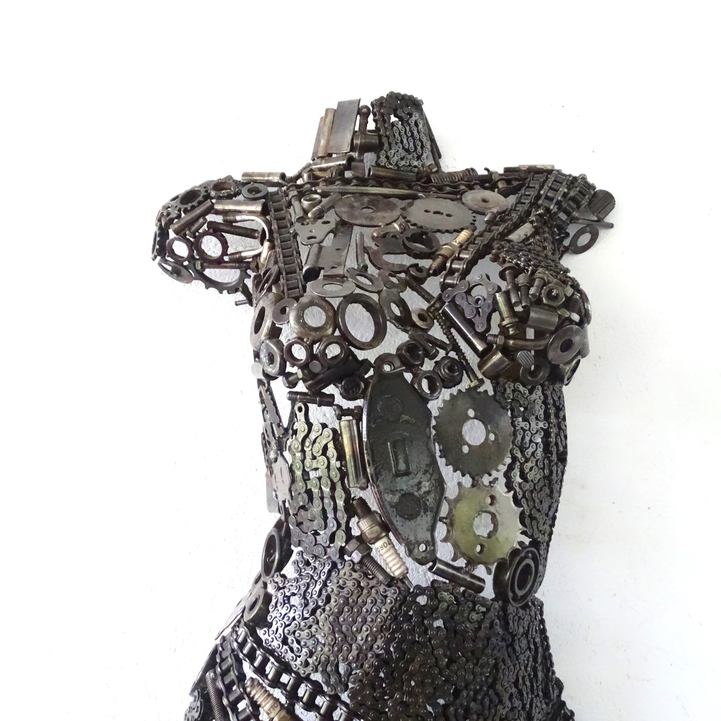 Détail de la poitrine d'une sculpture féminine en métal recyclé assemblé à la main, texture de soudure apparente