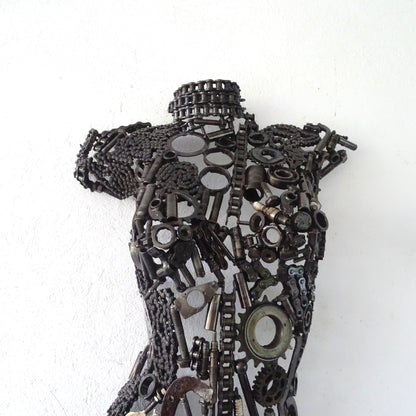 Détail poitrine sculpture femme en métal recyclé avec assemblage artisanal et textures métalliques visibles