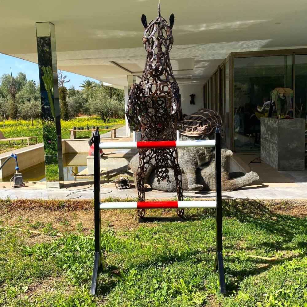 Vue de profil sculpture cheval saut d’obstacle en métal recyclé dans un jardin paysager moderne