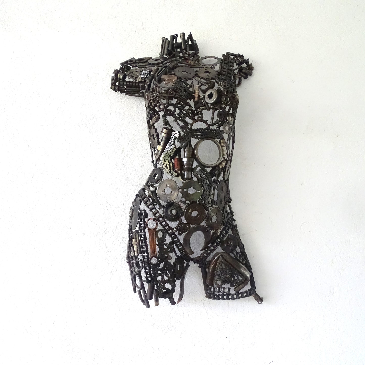 Sculpture demi-buste de femme en métal recyclé devant un mur de jardin, H75 x L42 cm, finition métal brut naturel