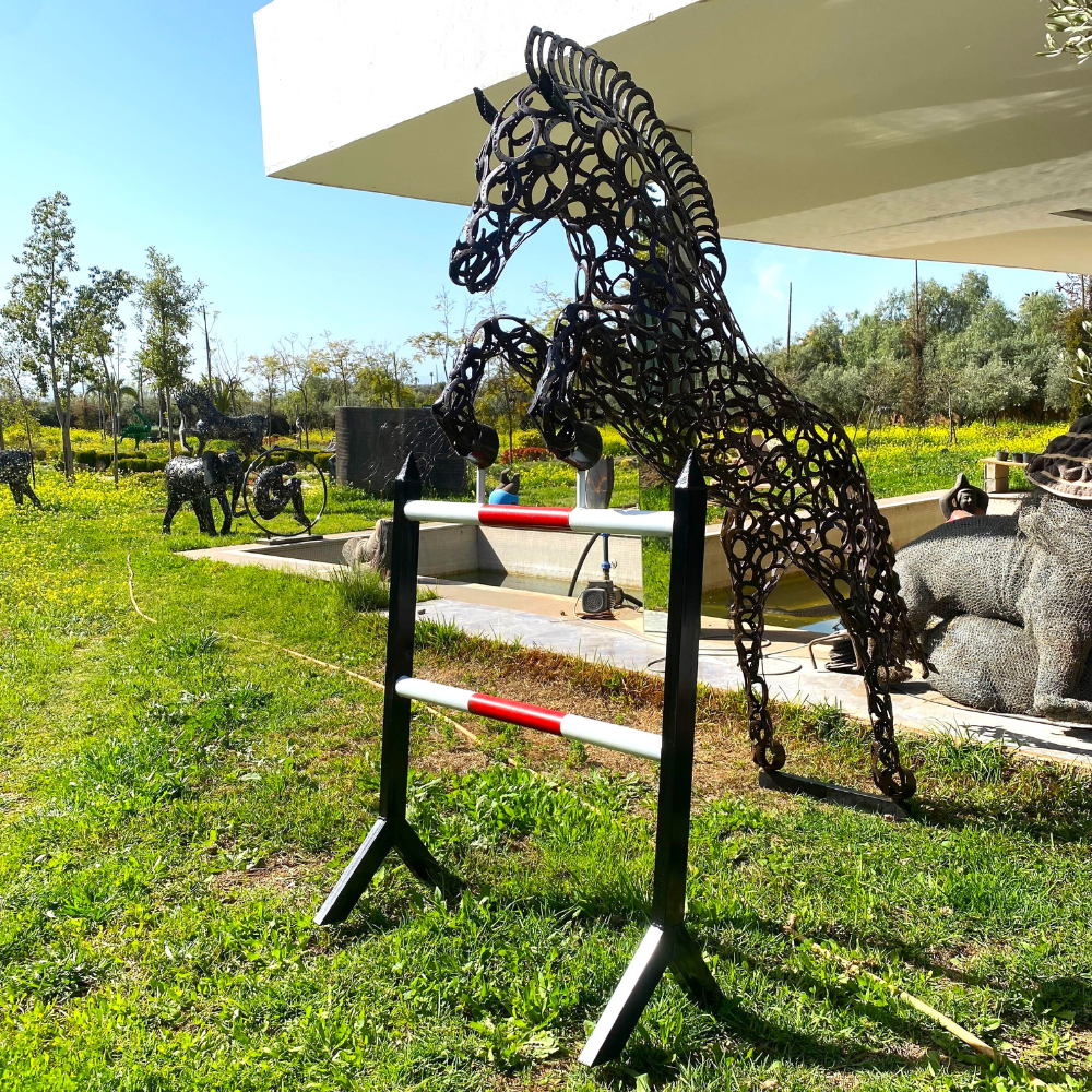 Sculpture cheval saut d’obstacle en fers à cheval recyclés installée dans un jardin contemporain