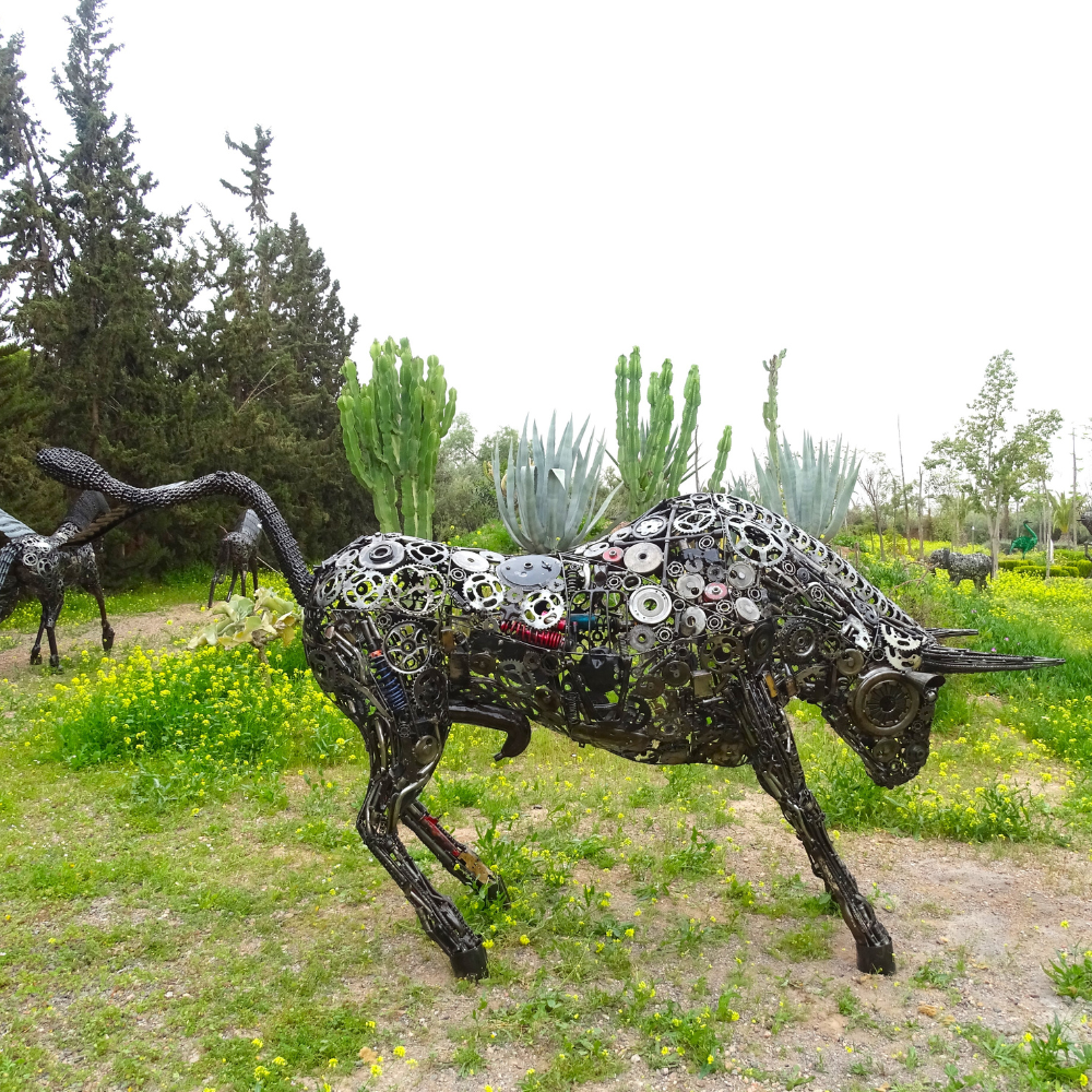 Sculpture taureau tête droite en métal recyclé installée dans un jardin paysager avec structure monumentale artisanale