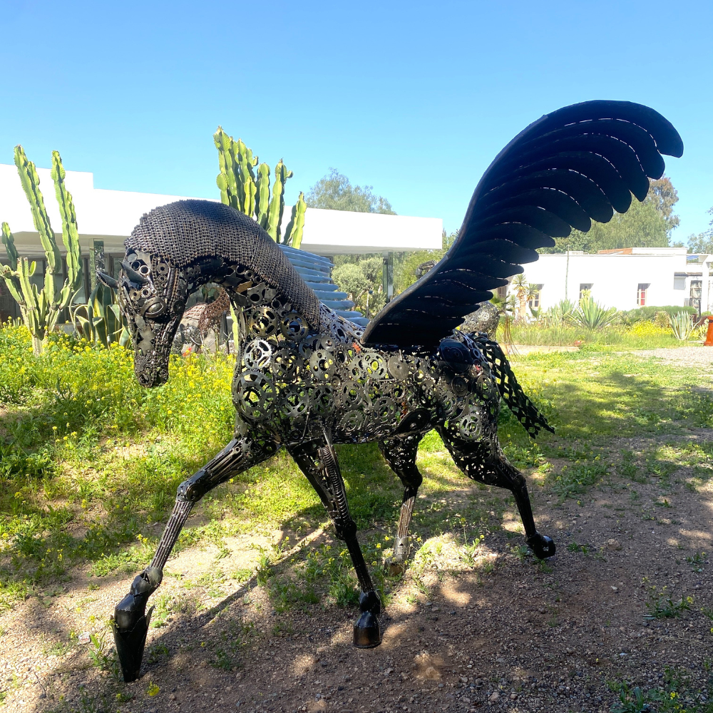 Vue latérale gauche cheval Pégase en métal recyclé dans un espace extérieur contemporain